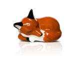 A ceramic figurine of a sleeping fox with a brown, white, and black color scheme, designed by Nora Fleming. Available at Be Charmed