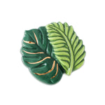 A ceramic mini charm depicting a stylized green fern with copper-colored veins, designed by Nora Fleming. Available at Be Charmed