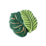 A ceramic mini charm depicting a stylized green fern with copper-colored veins, designed by Nora Fleming. Available at Be Charmed