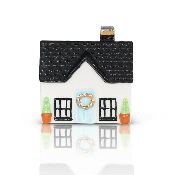 A house-shaped Nora Fleming Charm with a black roof, white front door, and decorative details. Available at Be Charmed