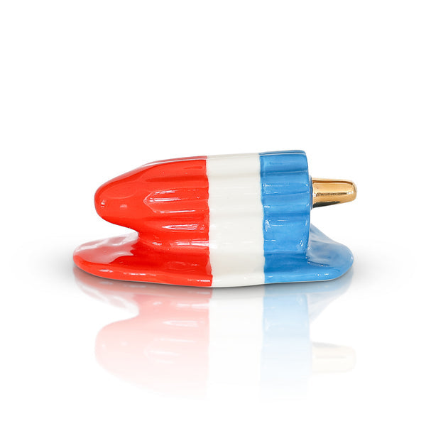 A Nora Flemingmini resembling a popsicle in red, white, and blue colors with a metallic gold accent. Available at Be Charmed