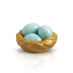 A ceramic egg nest Nora Fleming mini with two blue eggs inside, set against a white background. Available at Be Charmed