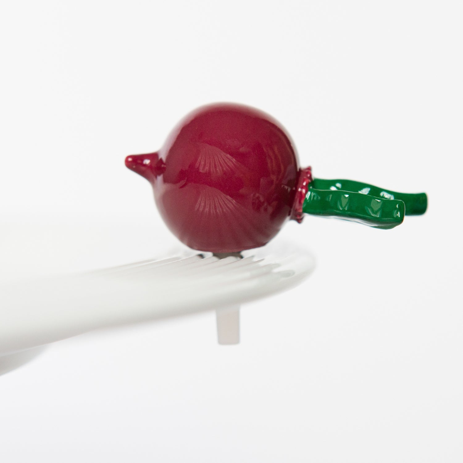 A red and green Nora Fleming Totally Rad radish mini figurine with a clip attached to its stem. Available at Be Charmed