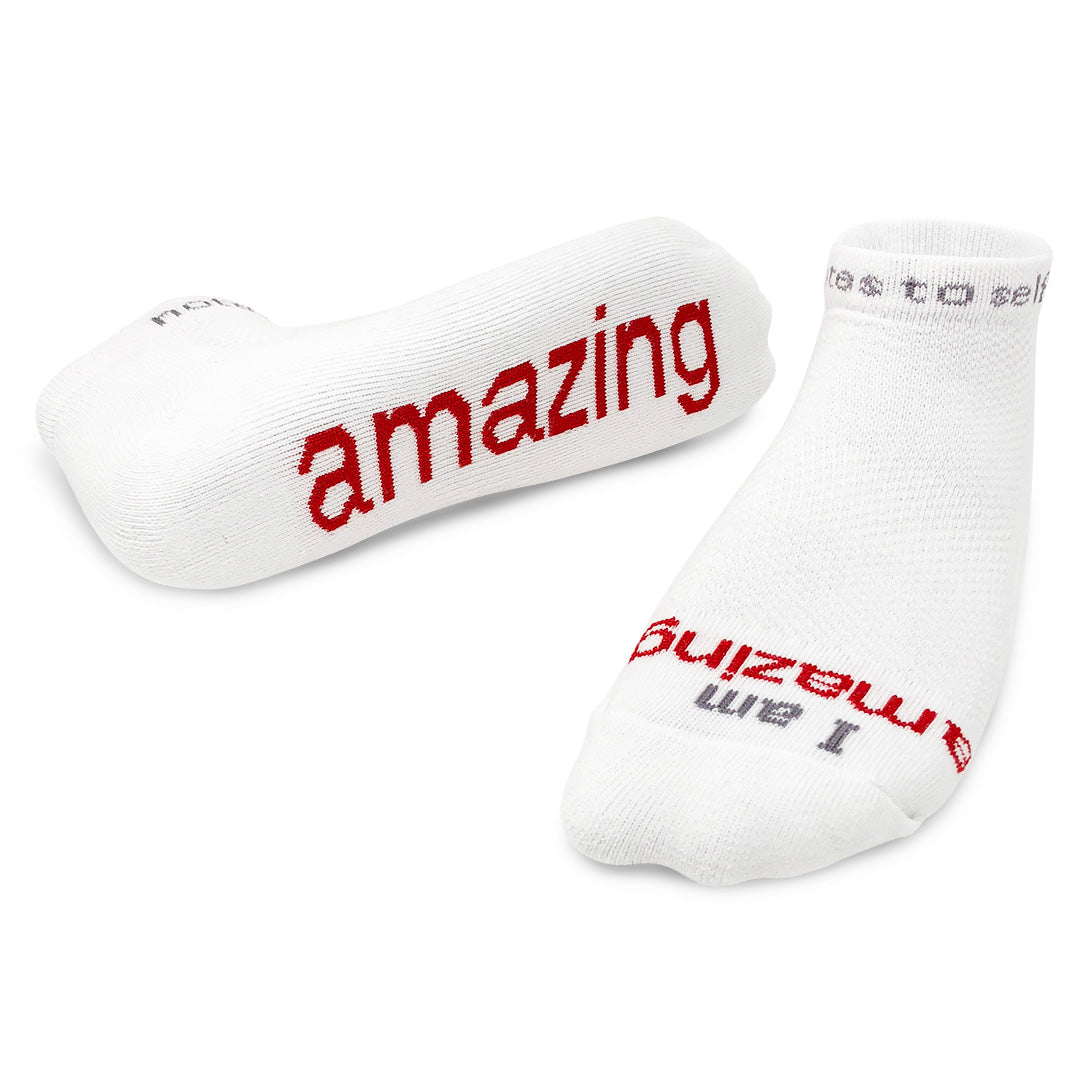 A pair of white crew socks with the word 'amazing' printed in red lettering. Available at Be Charmed