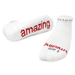 A pair of white crew socks with the word 'amazing' printed in red lettering. Available at Be Charmed