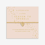 Gold heart bracelet on a pink card with 'A Littles & Co.' branding. Available at Be Charmed