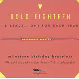 An 18-inch gold-dipped milestone birthday bracelet with a mix of beads, advertised by Lucky Feather, displayed against a red background with text detailing the product features. Available at Be Charmed