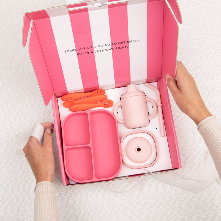 Open box view of Bella Tunno Garden Party Little Bites Set in pink, featuring a 3-in-1 cup, suction plate, starter bowl, and utensils, available at Be Charmed.