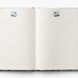 Open notebook with floral design on cover and pen on white background. Available at Be Charmed