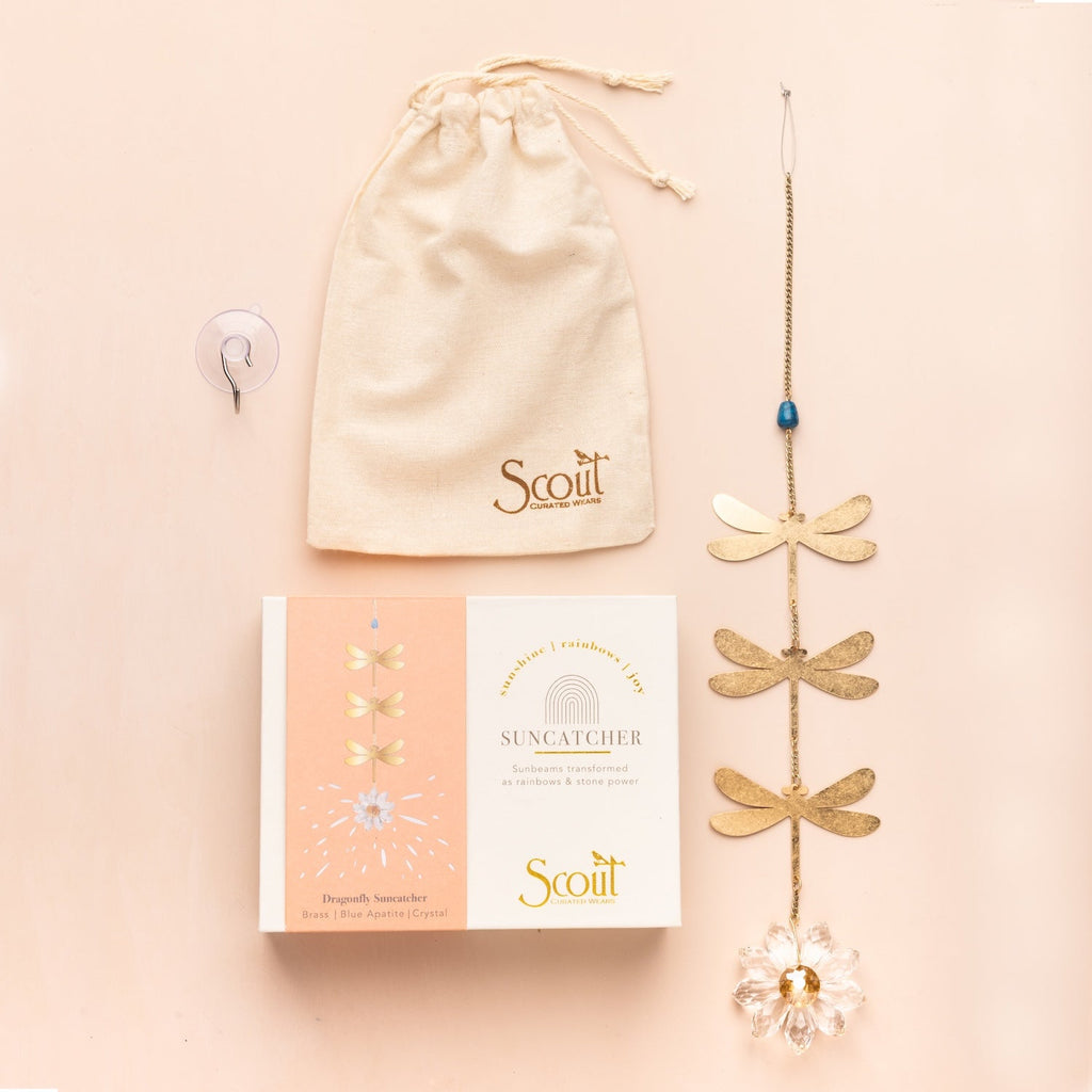Gold dragonfly suncatcher with packaging and drawstring bag on a beige background. Available at Be Charmed