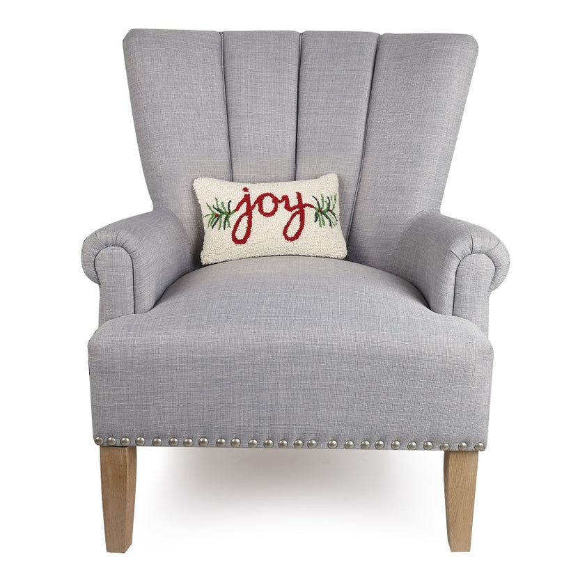 Gray armchair with a 'joy' pillow on a white background. Available at Be Charmed