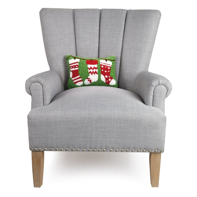 Gray armchair with a decorative pillow featuring Christmas stockings on a white background. Available at Be Charmed