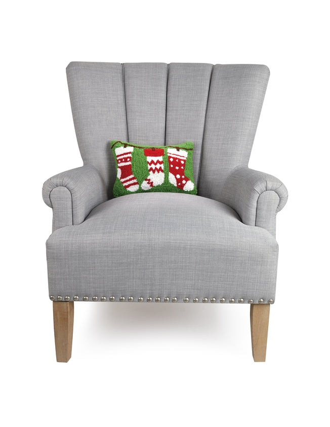 Gray armchair with a decorative pillow featuring Christmas stockings on a white background. Available at Be Charmed