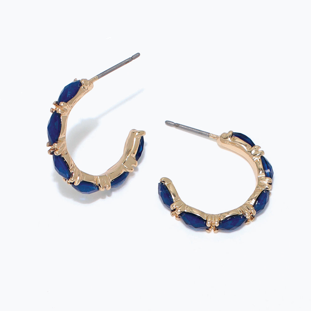Gold hoop earrings with blue stones on a white background. Available at Be Charmed
