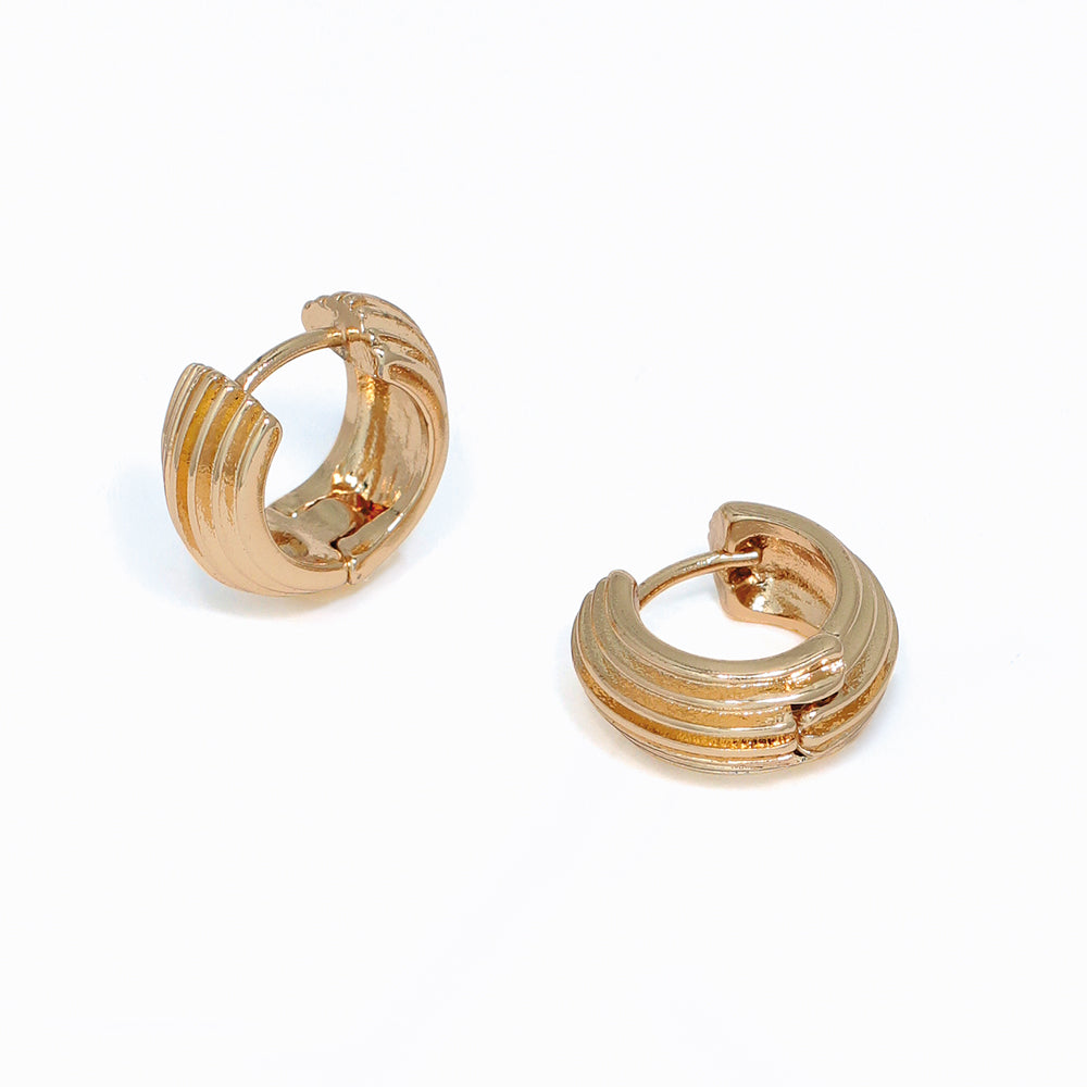Gold ribbed hoop earrings on a white background. Available at Be Charmed