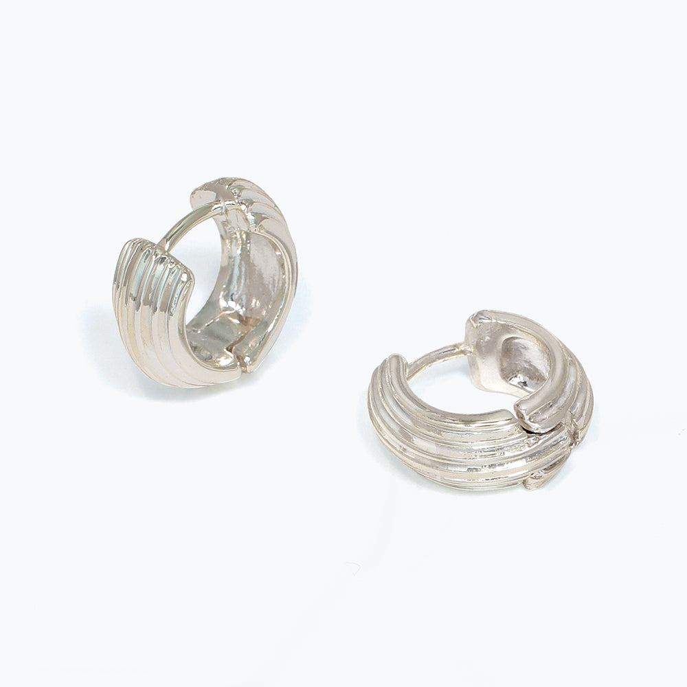 Pair of silver ribbed hoop earrings on a white background. Available at Be Charmed