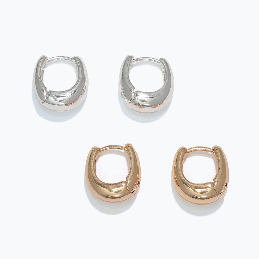 Two pairs of hoop earrings, one silver and one gold, on a white background. Available at Be Charmed