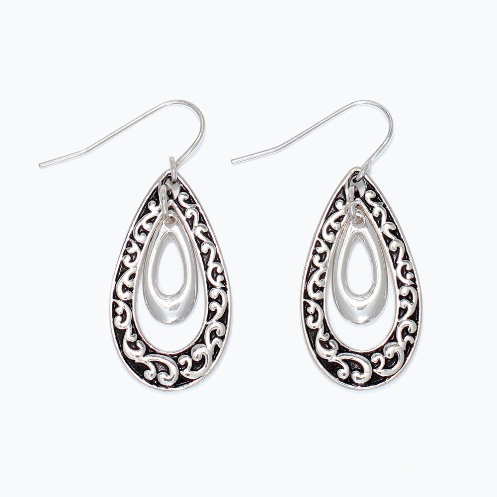 Silver teardrop earrings with intricate designs on a white background. Available at Be charmed