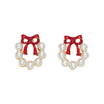Pair of wreath earrings with red bows and pearl-like centers on a white background. Available at Be Charmed. 