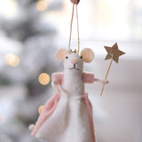 Decorative mouse ornament with a pink skirt and gold star, held against a blurred festive background. Available at Be Chamred