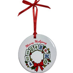 Round white ornament with a mahjong tile wreath, holly, a red bow, “Merry Mahjong” lettering and a red hanging ribbon. Available at Be Charmed.

