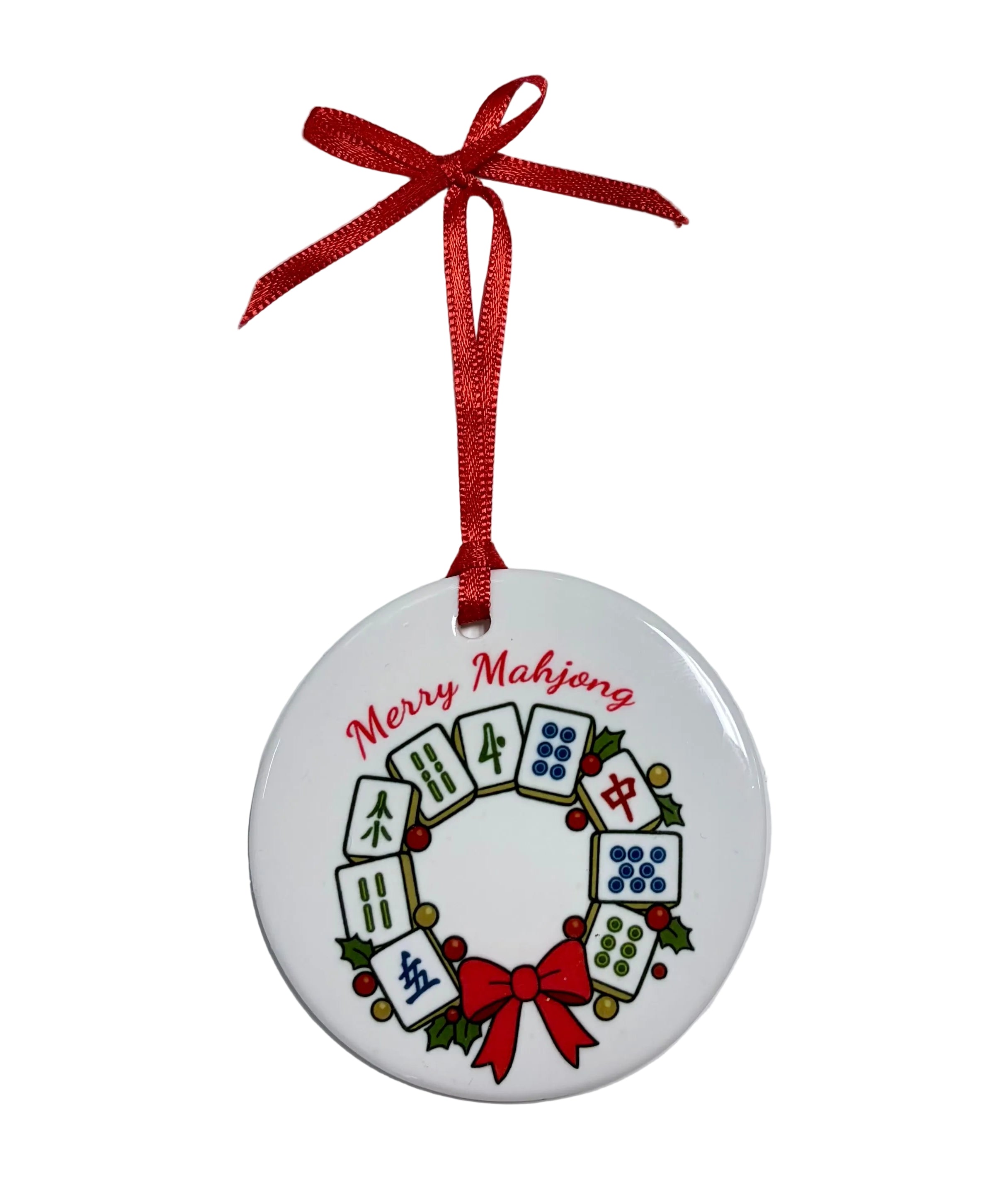 Round white ornament with a mahjong tile wreath, holly, a red bow, “Merry Mahjong” lettering and a red hanging ribbon. Available at Be Charmed.

