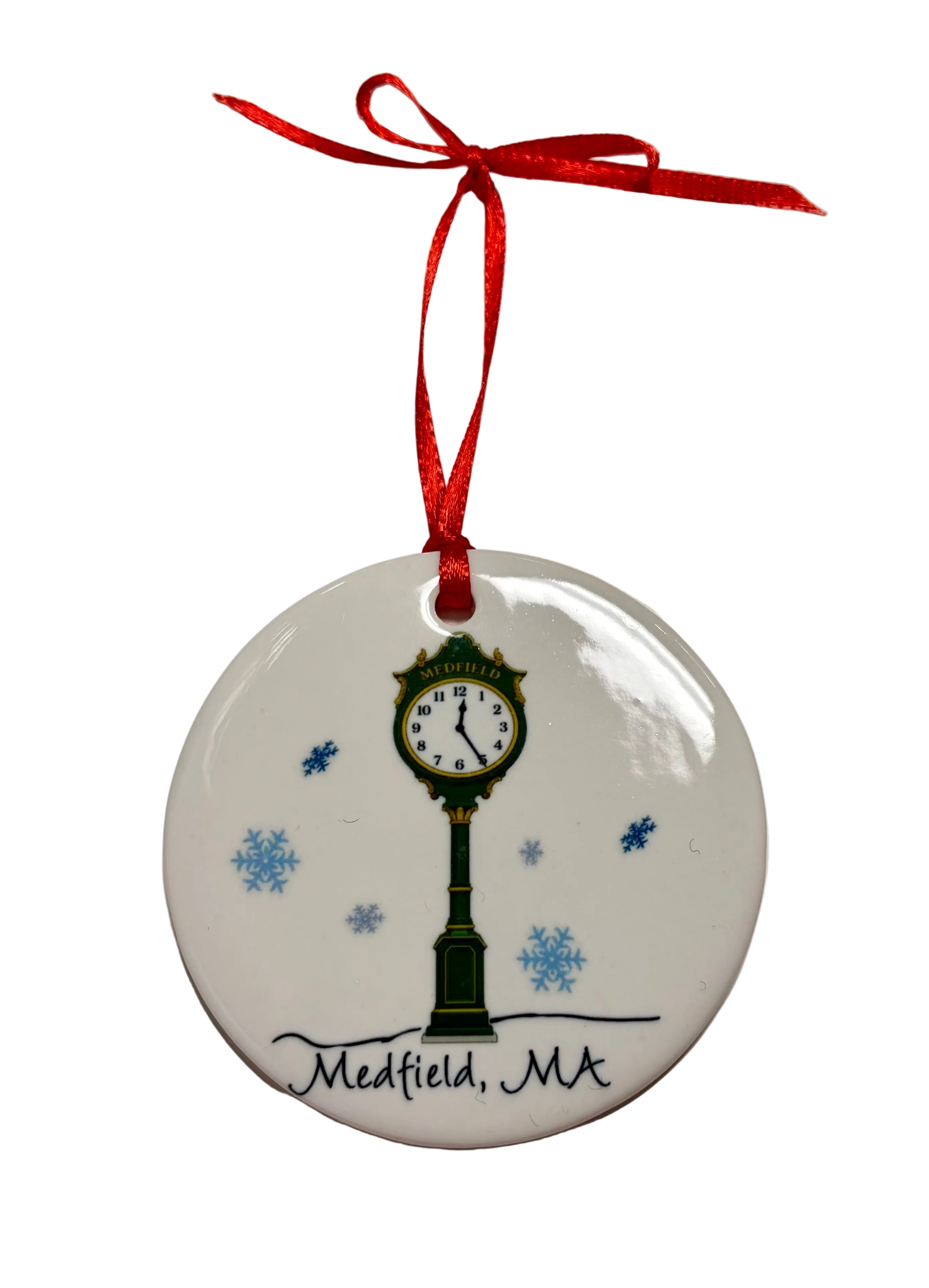 Round white ornament featuring a green street clock, blue snowflakes, “Medfield, MA” lettering and a red hanging ribbon. Available at Be Charmed.

