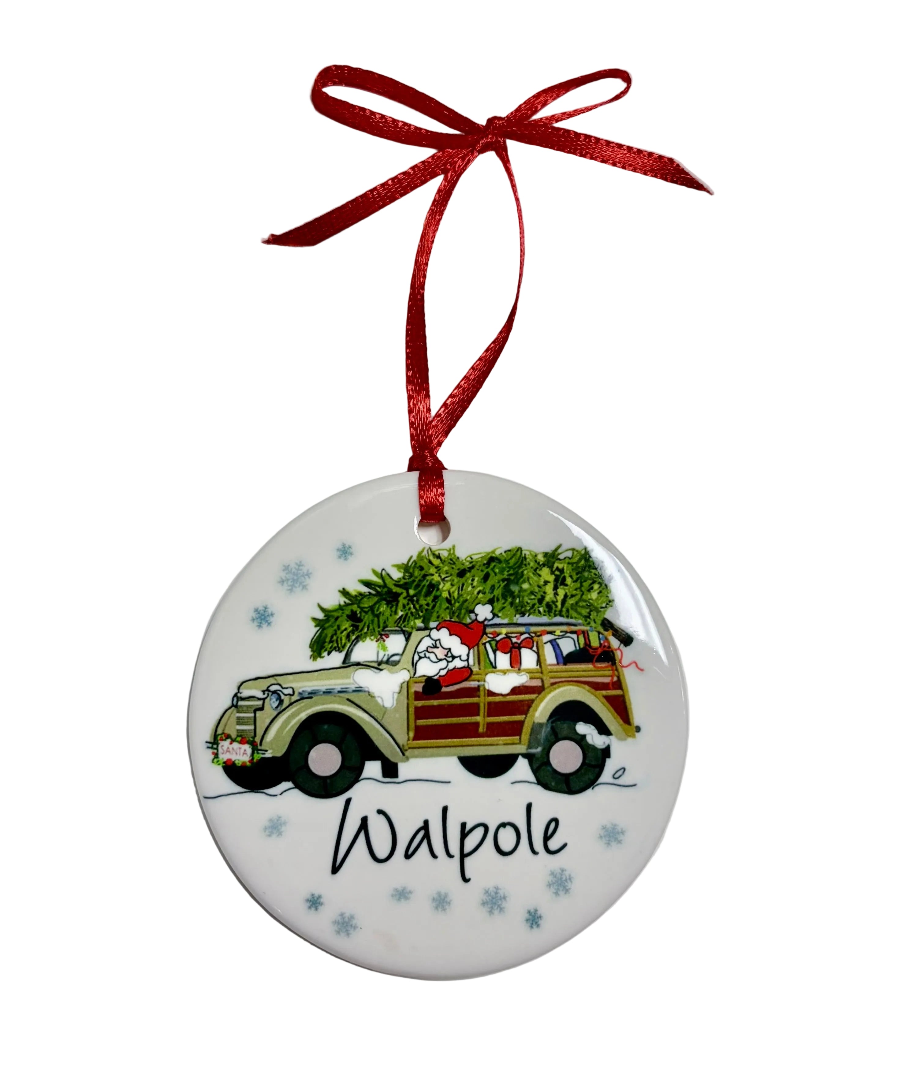  Round white ornament showing Santa driving a woodie wagon with gifts and a Christmas tree, blue snowflakes, “Walpole” lettering and a red ribbon. Available at Be Charmed.

