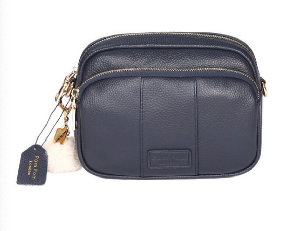 Navy Pom Pom London Original Bag – classic handcrafted leather crossbody with adjustable and interchangeable straps. Available at Be Charmed.