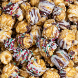 Close-up of christmas caramel popcorn with chocolate drizzle and sprinkles. Available at Be Charmed. 