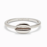 A silver-colored ring with a cowrie shell design on the top, with the phrase 'pura vida' stamped on the inside. Available at Be Charmed