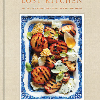 Book cover of 'The Lost Kitchen' with a dish of grilled peaches and honey on a beige background. Available at Be Charmed.  
