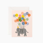 Greeting card with an elephant holding colorful balloons spelling 'Welcome Little One' on a light pink background. Available at Be Charmed
