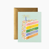 Greeting card with a colorful cake illustration and text, featuring a brown envelope on a white background. Available  at Be Charmed