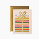 Greeting card with colorful striped design and gold bow, accompanied by a gold envelope on a white background. Available at Be Charmed