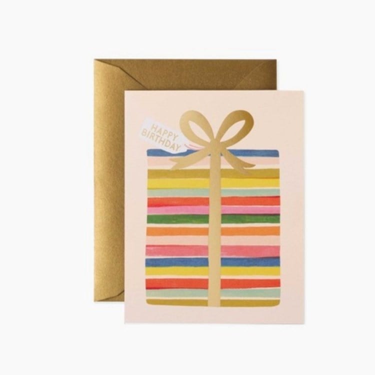 Greeting card with colorful striped design and gold bow, accompanied by a gold envelope on a white background. Available at Be Charmed