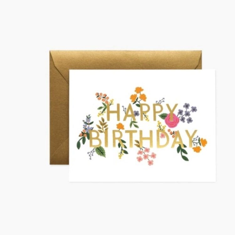 Greeting card with 'Happy Birthday' text and floral decorations on a white background. Available at Be Charmed