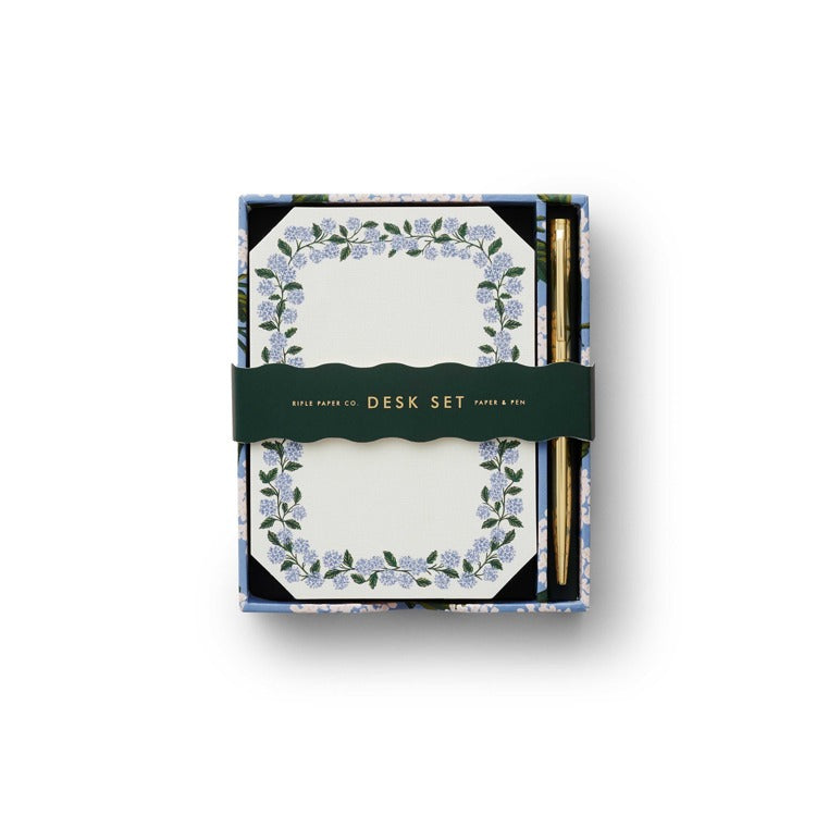 A note writing set by Rifle Paper Co with a hydrangea design, including a notepad and a pen, packaged in a box. Available at Be Charmed