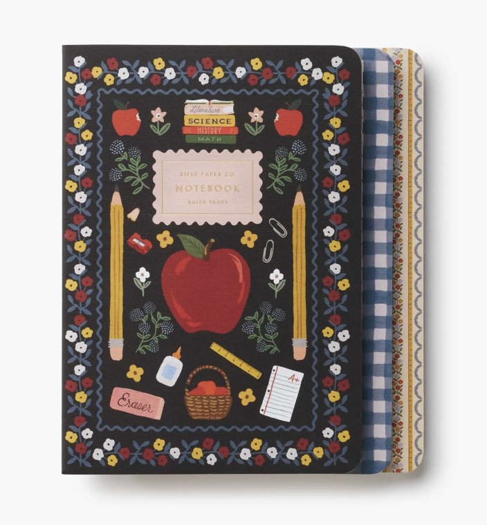 A School themed notebook with a black cover decorated with a colorful floral border, red apple, yellow pencils, and school supplies. The notebook is shown closed with its patterned paper covers partially visible on the right side. Available at Be Charmed