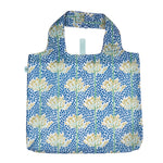 A reusable fabric tote bag with a blue background, covered in a pattern of white water lilies with green stems and vertical blue speckled stripes. Available at Be Charmed