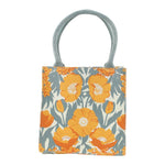 A square canvas tote bag featuring a retro floral pattern with orange poppies and blue-gray leaves on a cream background, complete with two thick braided blue-gray shoulder straps. Available at Be Charmed