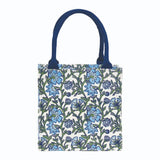 Floral patterned tote bag with blue handles on a white background. Available at Be Charmed
