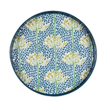 A round decorative tray with a dark blue rim, featuring a pattern of yellow and white flowers with green stems on a blue speckled background. Available at Be Charmed
