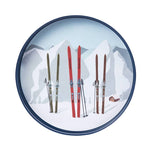 Ski design on a round blue plate with a snowy mountain background. Available at Be Charmed