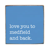 Blue sign with white text 'love you to medfield and back.' Available at Be Charmed