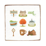 Decorative blanket with illustrations of a town scene, including buildings, a clock, and a cup. Available at Be Charmed