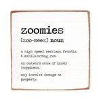 A 6 x 6 wooden block with a definition of 'zoomies' printed on it, placed against a white background. Available at Be Charmed