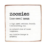 A 6 x 6 wooden block with a definition of 'zoomies' printed on it, placed against a white background. Available at Be Charmed