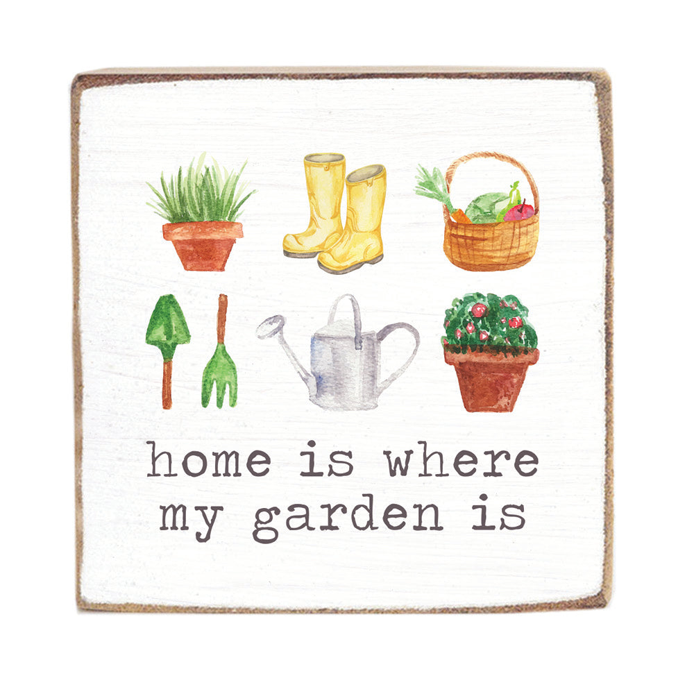 Decorative wood block with gardening-themed illustrations and text 'home is where my garden is' on a white background. Available at Be Charmed