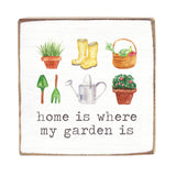 Decorative wood block with gardening-themed illustrations and text 'home is where my garden is' on a white background. Available at Be Charmed